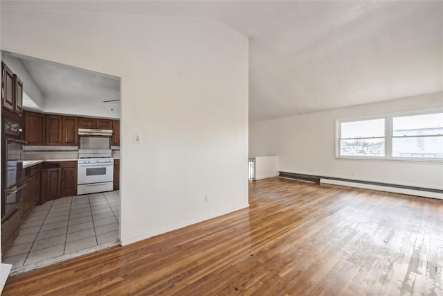 kitchen featuring white gas range oven, backsplash, dark brown cabinets, hardwood / wood-style floors, and lofted ceiling