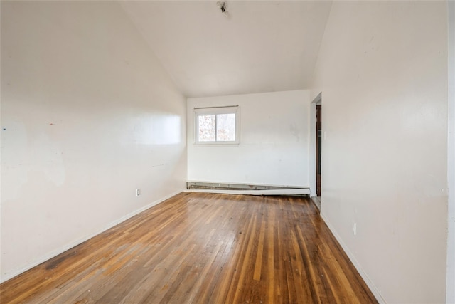 empty room featuring dark hardwood / wood-style flooring, a baseboard radiator, and vaulted ceiling