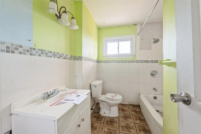 full bathroom with tiled shower / bath combo, toilet, tile walls, and vanity