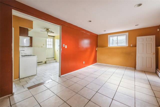 spare room with light tile patterned floors, a baseboard radiator, plenty of natural light, and ceiling fan