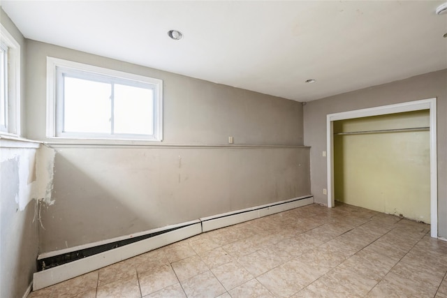 unfurnished bedroom with a closet and a baseboard heating unit