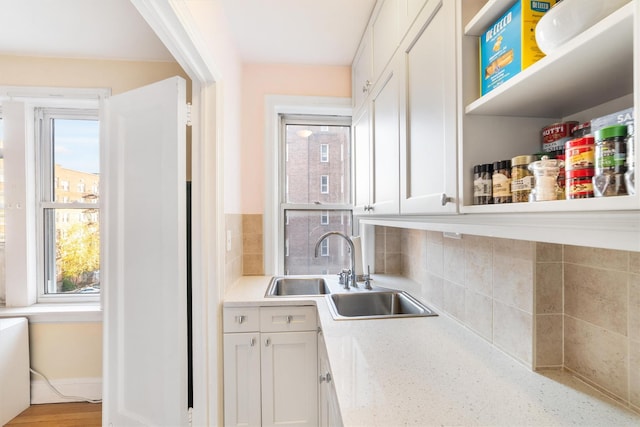 kitchen featuring white cabinets, decorative backsplash, and sink