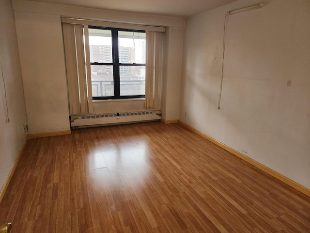 unfurnished room with light hardwood / wood-style flooring and a baseboard heating unit