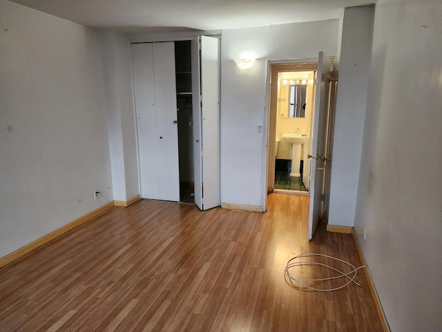 unfurnished bedroom with a closet, sink, and light hardwood / wood-style flooring