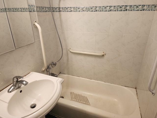 bathroom with tile walls, tiled shower / bath, and sink