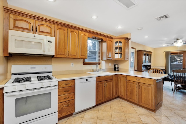 kitchen with plenty of natural light, white appliances, sink, and kitchen peninsula