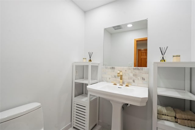 bathroom with decorative backsplash and toilet