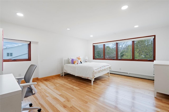 bedroom with light hardwood / wood-style floors and baseboard heating