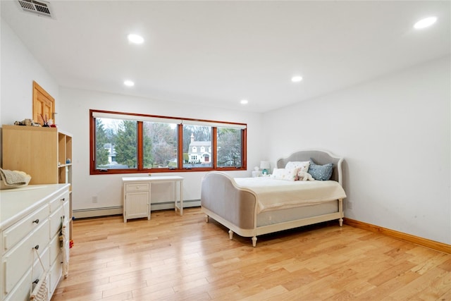 bedroom with light hardwood / wood-style floors and baseboard heating