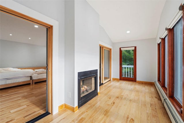 living room with a baseboard heating unit, lofted ceiling, and light hardwood / wood-style flooring