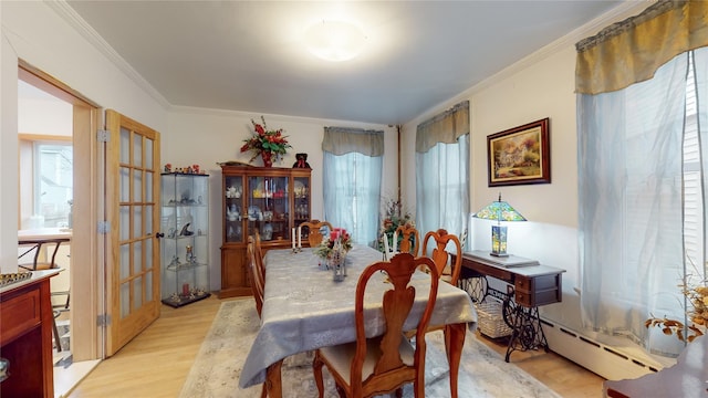 dining room with light hardwood / wood-style floors, crown molding, and a baseboard radiator