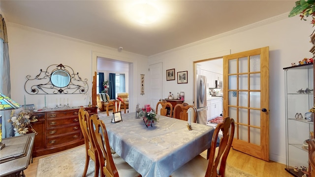 dining space featuring crown molding, light hardwood / wood-style flooring, and french doors