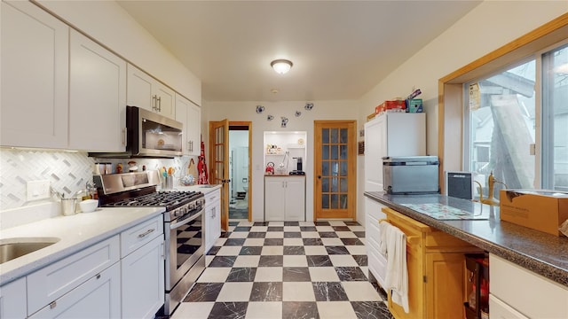 kitchen featuring white cabinets, stainless steel appliances, and tasteful backsplash