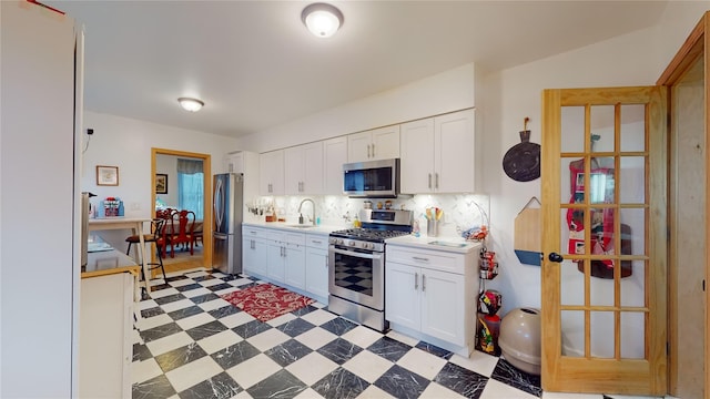 4 Elizabeth St, Port Jervis, NY 12771 - kitchen with appliances with stainless steel finishes, light countertops, white cabinetry, backsplash, and light floors