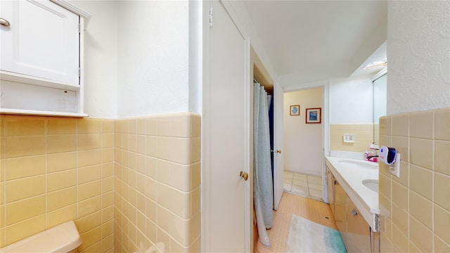 bathroom featuring tile patterned flooring, vanity, tile walls, and toilet