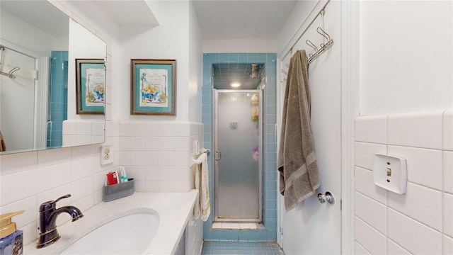 bathroom featuring an enclosed shower, vanity, and tile walls