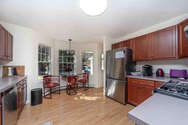 kitchen with a wealth of natural light, pendant lighting, stainless steel appliances, and light hardwood / wood-style flooring