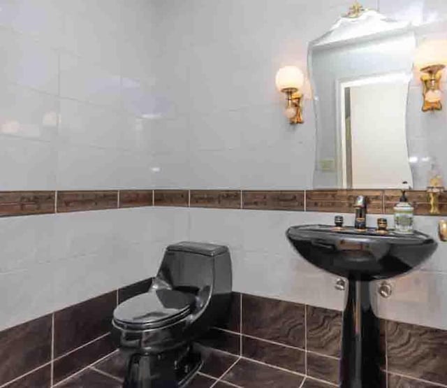 bathroom featuring tile patterned flooring, toilet, and tile walls