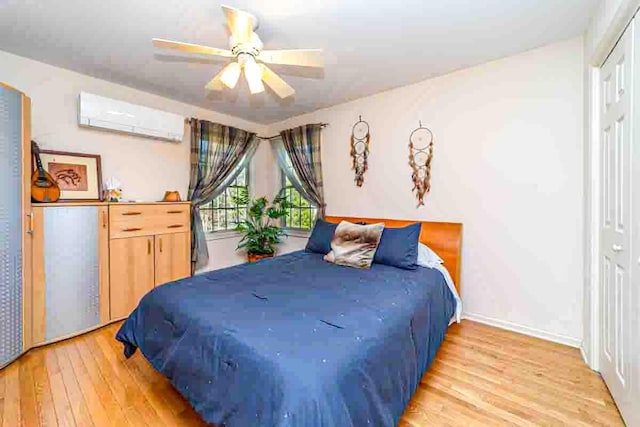 bedroom featuring ceiling fan, a closet, an AC wall unit, and light hardwood / wood-style flooring