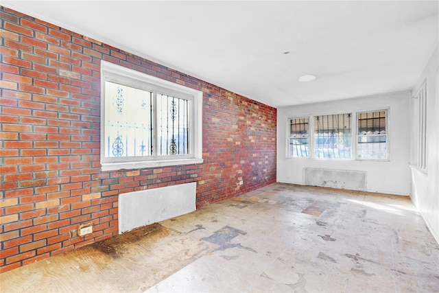 spare room featuring brick wall