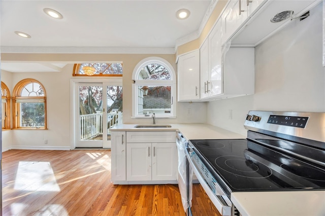 kitchen with appliances with stainless steel finishes, light hardwood / wood-style floors, white cabinetry, and sink