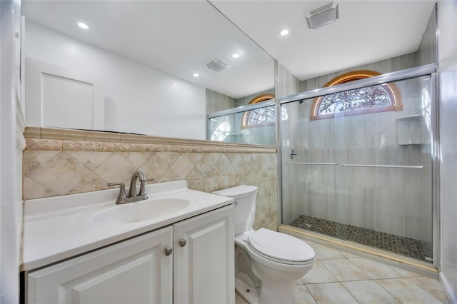 bathroom featuring walk in shower, tile patterned flooring, toilet, vanity, and tile walls