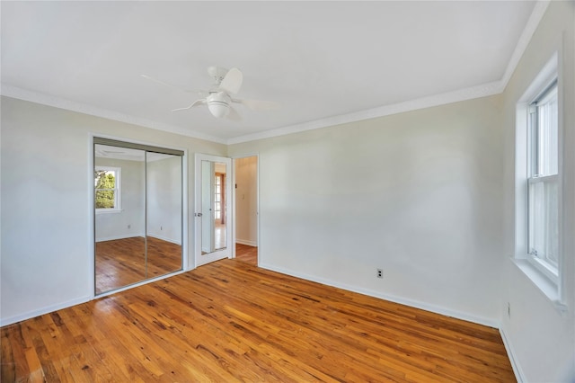 unfurnished bedroom featuring a closet, hardwood / wood-style flooring, ceiling fan, and ornamental molding