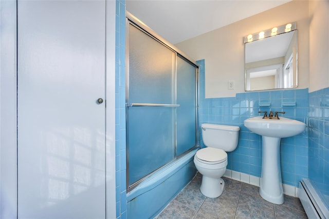 bathroom featuring tile patterned flooring, shower / bath combination with glass door, baseboard heating, and tile walls