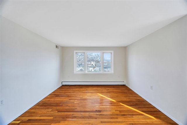 spare room with a baseboard radiator and hardwood / wood-style flooring