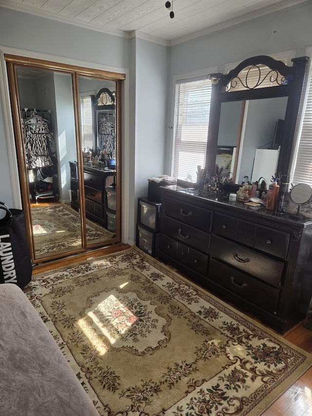 bedroom with wooden ceiling, wood-type flooring, ornamental molding, and a closet