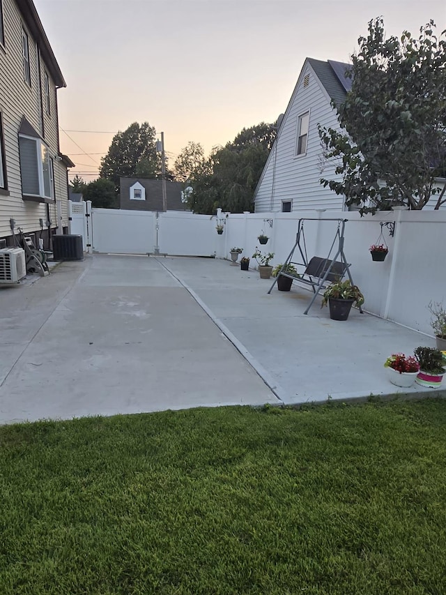 patio terrace at dusk featuring a yard and cooling unit