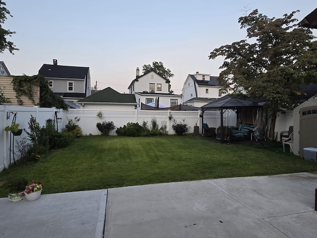 yard at dusk featuring a gazebo and a patio area