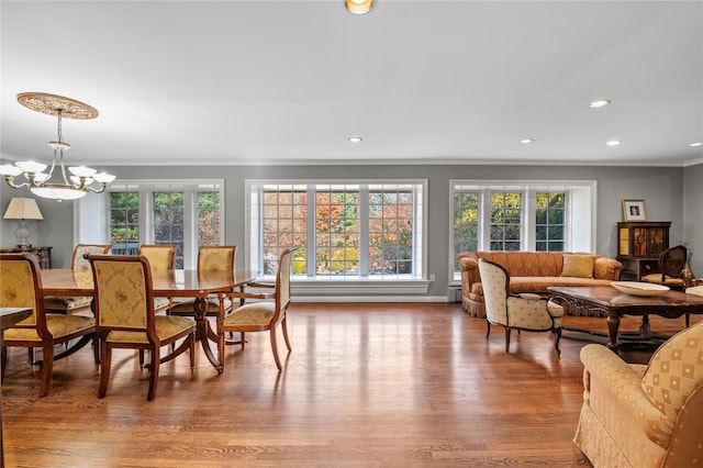 dining area featuring hardwood / wood-style flooring, crown molding, a wealth of natural light, and an inviting chandelier