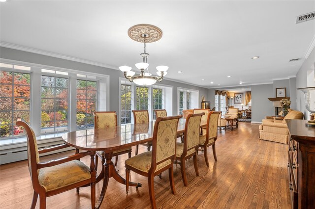 dining room with ornamental molding, light hardwood / wood-style flooring, baseboard heating, and a notable chandelier