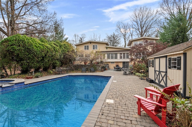 view of pool with a storage unit, an in ground hot tub, and a patio