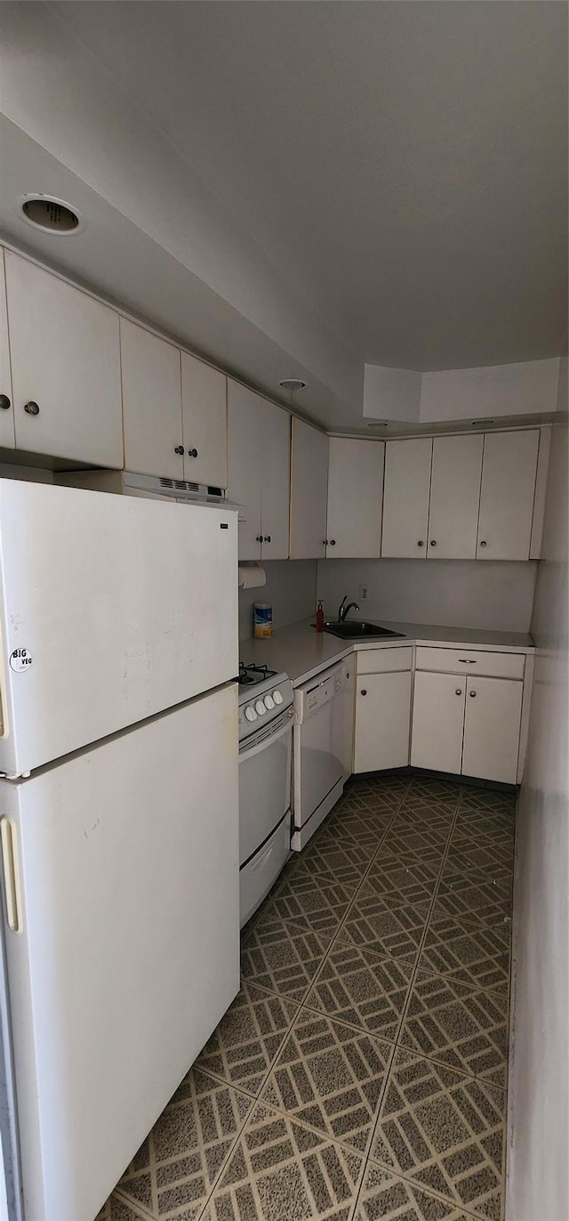 kitchen with white cabinetry, white appliances, sink, and dark tile patterned floors