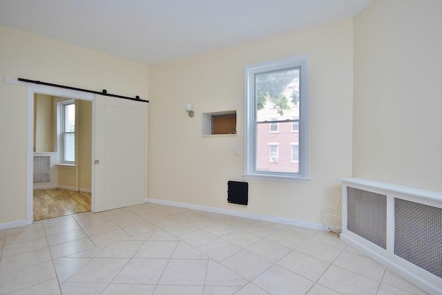 spare room with a barn door and light tile patterned floors