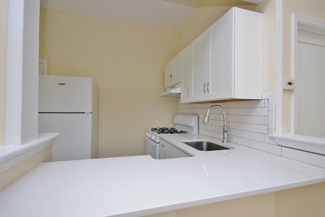 kitchen with white cabinetry, sink, kitchen peninsula, white appliances, and decorative backsplash