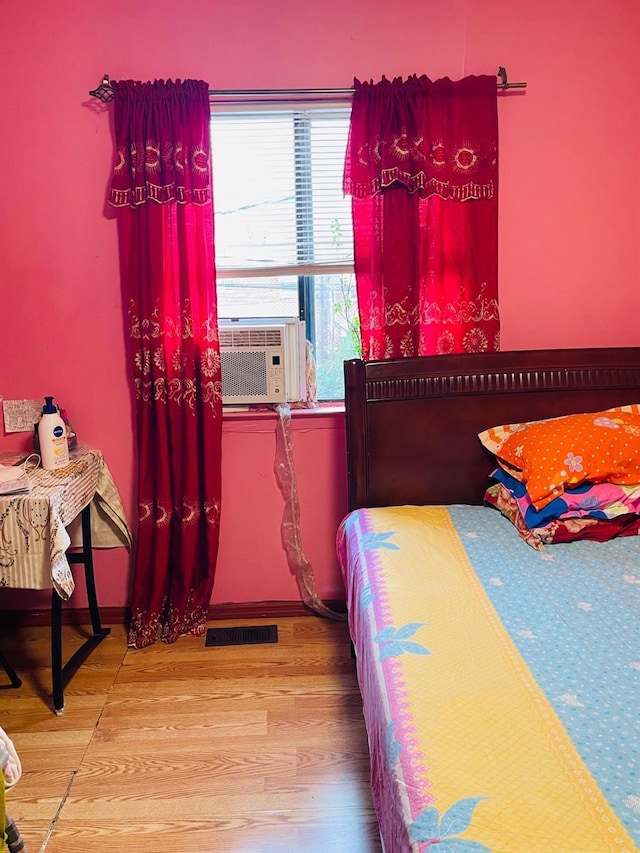 bedroom featuring cooling unit, multiple windows, and hardwood / wood-style floors