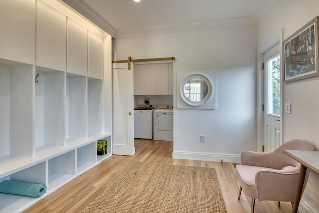 living area with a barn door, light hardwood / wood-style flooring, washer and clothes dryer, and ornamental molding