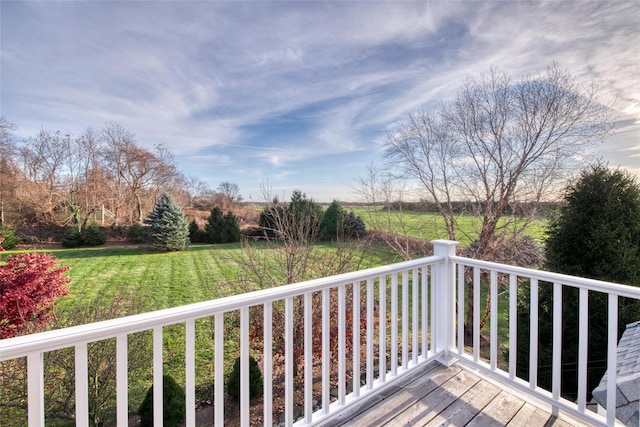 wooden terrace featuring a rural view and a yard