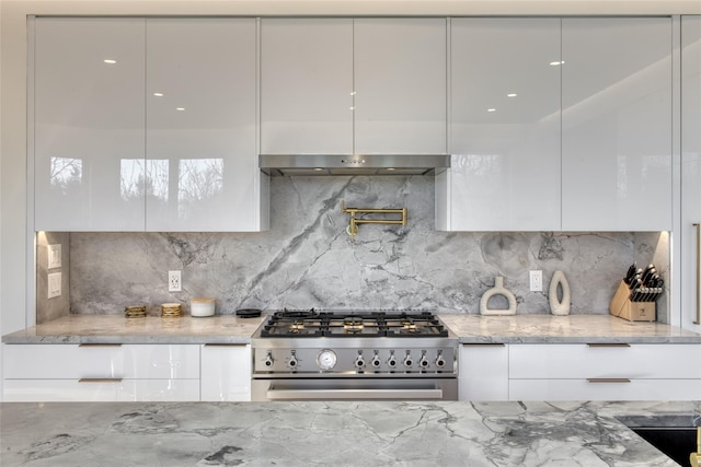 kitchen featuring white cabinetry, backsplash, light stone countertops, and stainless steel stove