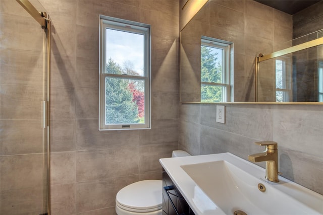 bathroom with tile walls, vanity, a shower with door, and toilet