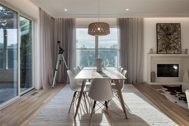 465 Sound Shore Rd, Aquebogue, NY 11901 - dining room with light wood-style flooring, a glass covered fireplace, plenty of natural light, crown molding, and recessed lighting