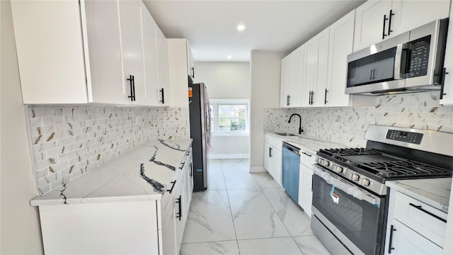 kitchen with white cabinets, light stone counters, sink, and appliances with stainless steel finishes