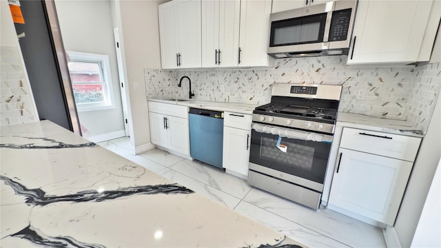 kitchen featuring light stone counters, sink, white cabinets, and appliances with stainless steel finishes