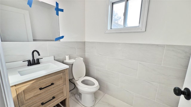 bathroom with vanity, toilet, and tile walls