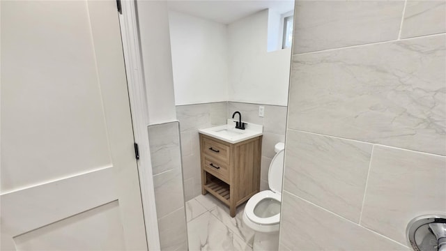 bathroom with vanity, toilet, and tile walls