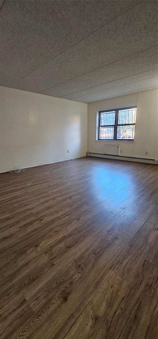 unfurnished room featuring dark hardwood / wood-style flooring and a baseboard heating unit