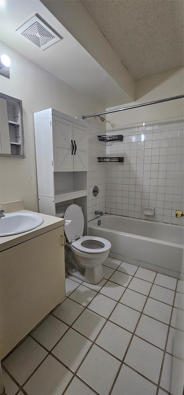 full bathroom featuring tile patterned floors, a textured ceiling, toilet, vanity, and tiled shower / bath